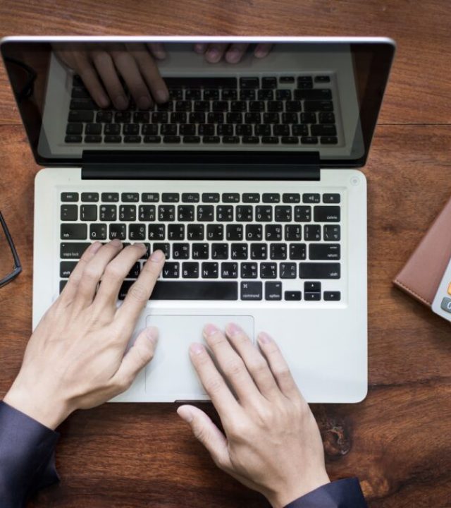 top-view-business-man-hands-working-laptop-tablet-pc-wooden-desk-min-1024x683